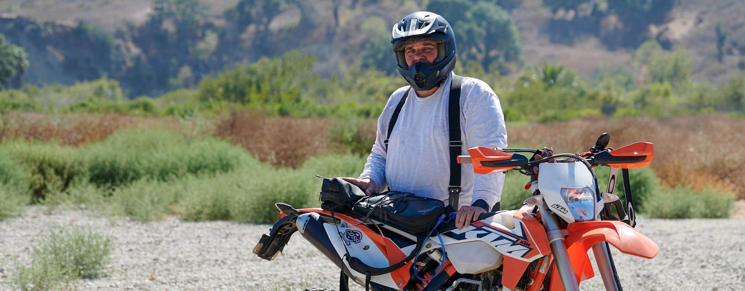 Chris Compton Founder & CEO of Clydesdale Gear standing off to the side of his motorcycle looking at the camera with the Enduro Pack laying on the seat of the motorcycle.