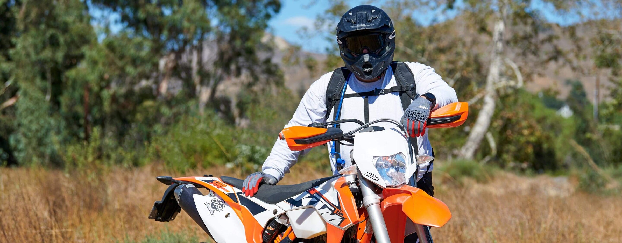 Front view of a guy looking at the camera standing behind his enduro motorcycle wearing the Clydesdale Gear Hydration Pack.